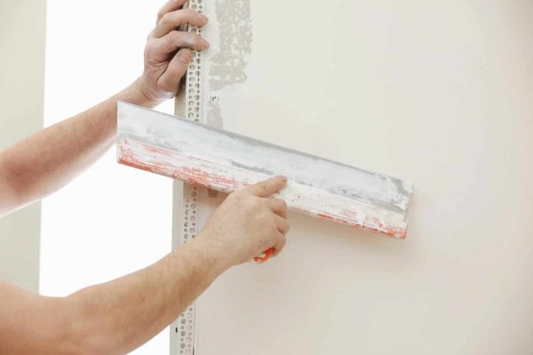 builder-in-protective-mask-using-a-trowel-to-add-plaster-plastering-wall-with-putty-knife-close-up-e1708603242972.jpg