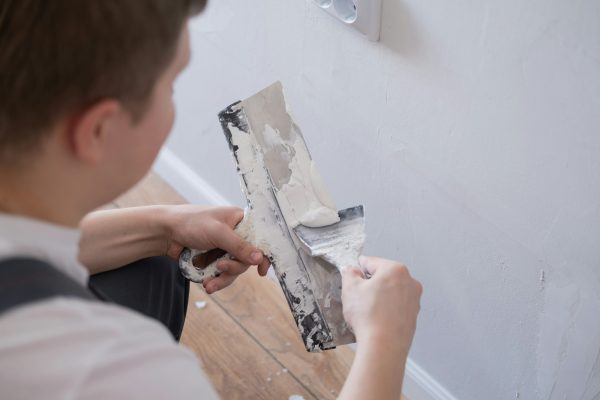 man-removes-holes-and-bumps-on-the-wall-with-a-spatula-and-plaster.jpg